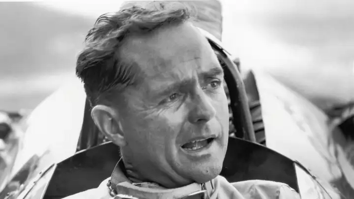 American Grand Prix racing car driver Phil Hill sits in his car and talks to the out-of-frame pit