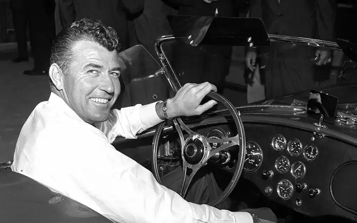 Carroll Shelby seated in the driver's seat of a roadster