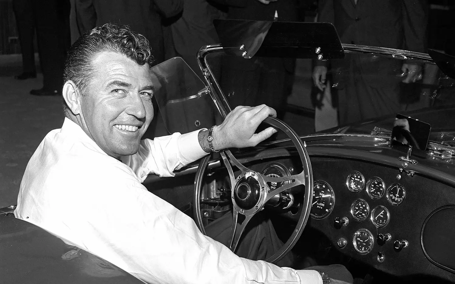 Carroll Shelby seated in the driver's seat of a roadster